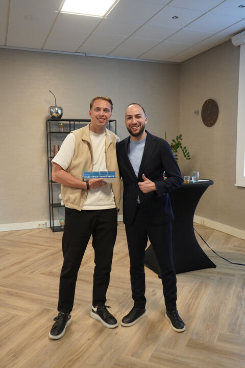 Twee collega&rsquo;s van Nutscontact met een award tijdens een uitreiking op kantoor