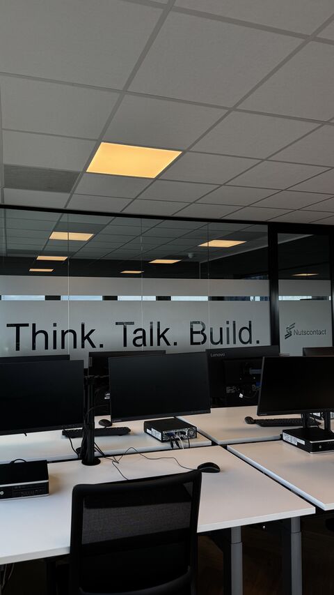 De kantoormuur van Nutscontact met de tekst Think. Talk. Build. boven de werkplekken