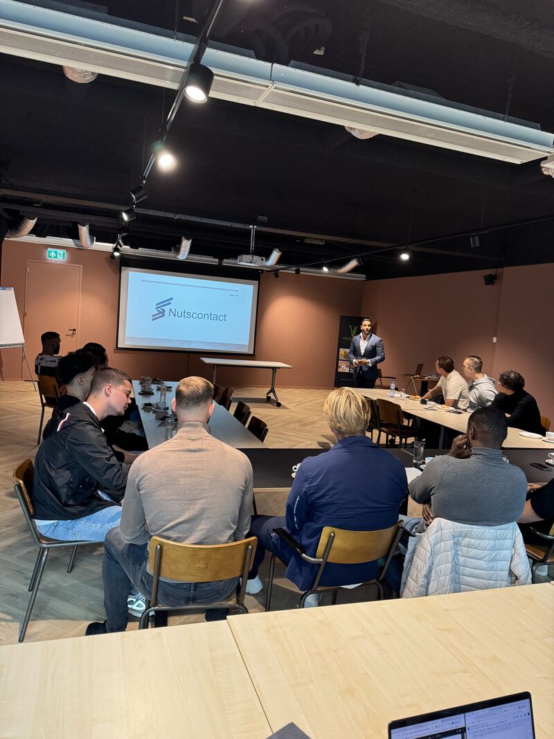 Trainingszaal van Nutscontact met het logo op het scherm en het team in de zaal